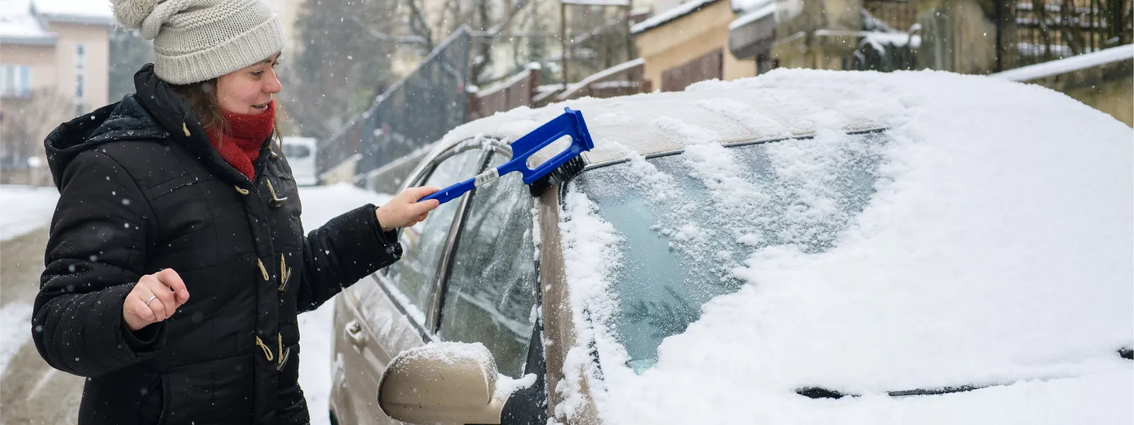 žena zametá sníh z auta